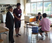 （右）学生ボランティアから話を聞く濱田総長（左端）。