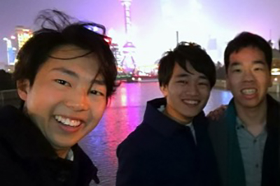 Selfie-style photo of three undergraduate students with cityscape of Shanghai, China in background..
