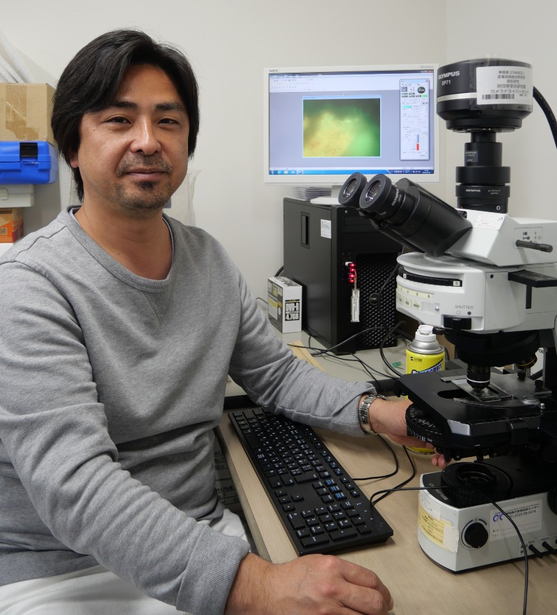 Associate Professor Yohey Suzuki at the microscope with rock sample
