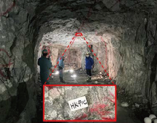 「HK中心」と書かれた白い板を天井部分に張り付けてあるトンネルとヘルメットをかぶった3人
