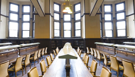 Room with several windows and rows of long tables and chairs