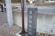 （左）「津波襲来の碑」（奥の更地部分に以前建物あり）