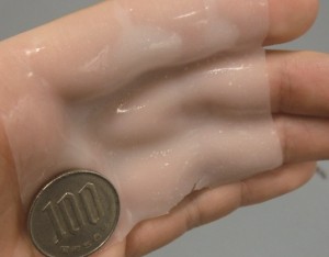 © 2015 Takao Someya. Adhesive gel with superior biocompatibility that can be formed into patterns with light.This novel type of gel can fit to the shape of the fingers when applied to the hand. The gel surface has strong adhesion, and a 100 yen coin does not fall off even when shaken.
