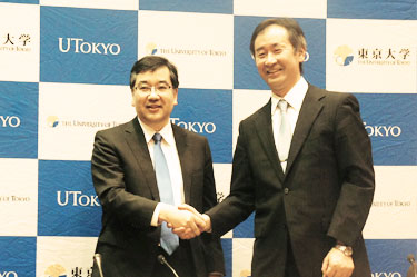 Professor Kajita smiling and shaking hands with President Gonokami