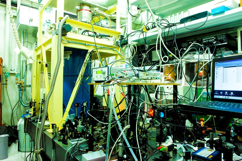 Figure 2: Experimental apparatus for creating excitons at high density and ultra-low temperatures<br>An ultra-low temperature below 0.1 K is maintained in the laboratory, which is equipped with apparatus for observing light and matter, and includes a laser for creating excitons. Because the laser has a heating effect, the temperature will increase if the semiconductor is simply irradiated with the laser. The key to achieving Bose-Einstein condensation of excitons lies in maintaining a low temperature while irradiating the semiconductor with high-energy laser light.<br>Credit: Gonokami, Yumoto, and Yoshioka Laboratory, Graduate School of Science, The University of Tokyo.
