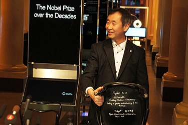 Professor Kajita showing the chair with his signature and that of co-winner Professor Emeritus Arthur B. McDonald