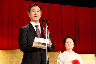 Professor Kajita giving a speech that reflects his sincere personality. Mrs. Kajita is watching him from behind