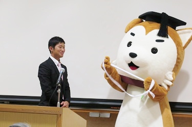 The tournament mascot Ichi-ko gives the sash to Nagoya University, the next hosting university (Picture provided by Gakushi-kai)