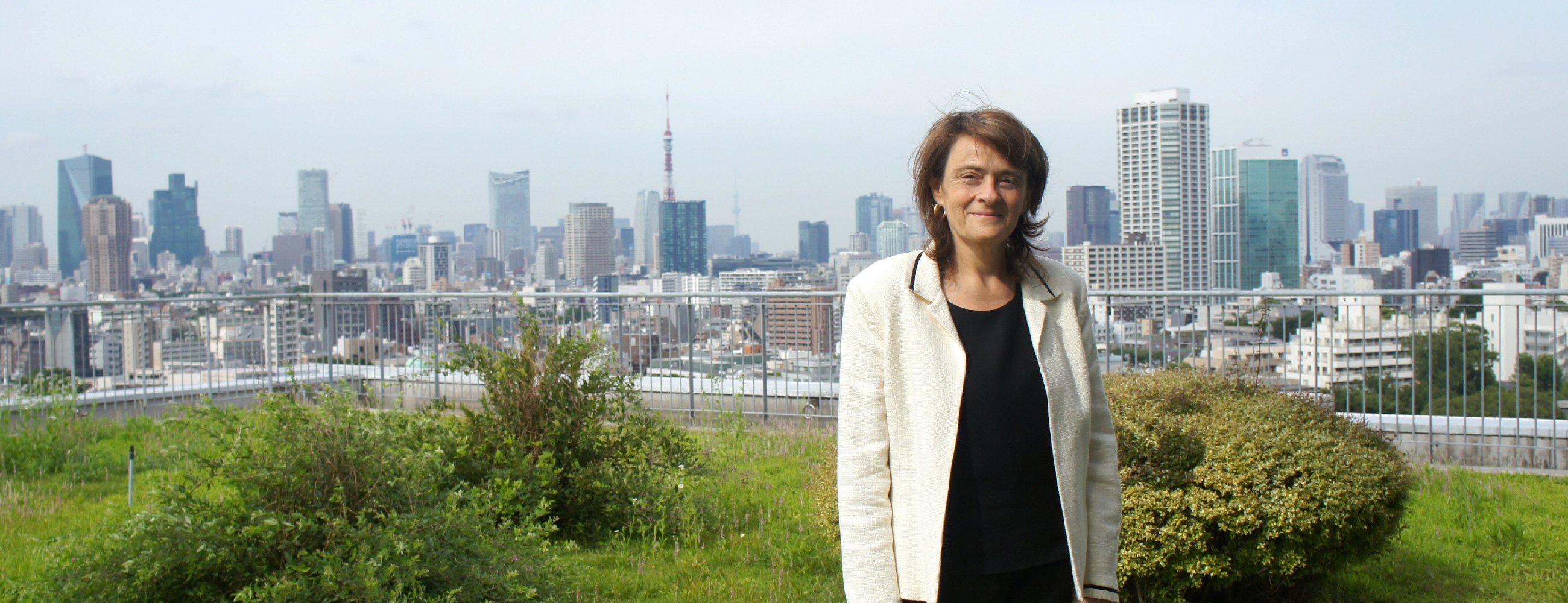 Researcher standing on the roof of a building with a cityscape in the background