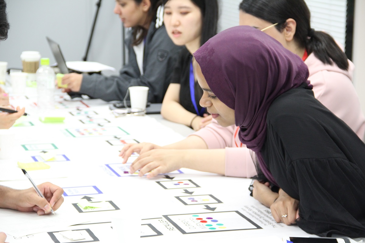 Some students examine a number of game pieces on a table