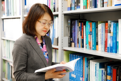 Portrait of Professor Kaoru Sato reading a book in her office