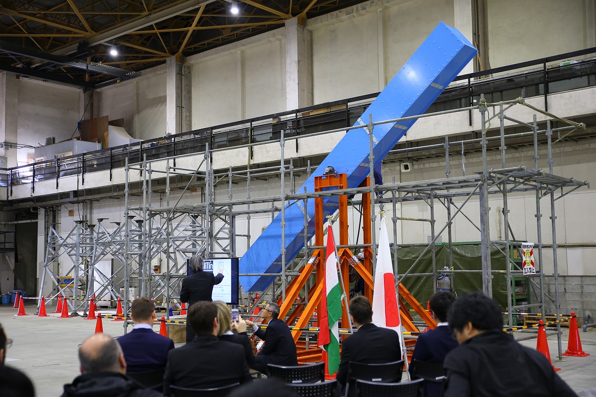 A group of people sit in front of a big blue machine