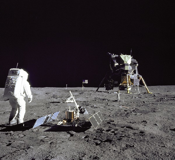 An astronaut standing on the moon looks at the lunar lander.
