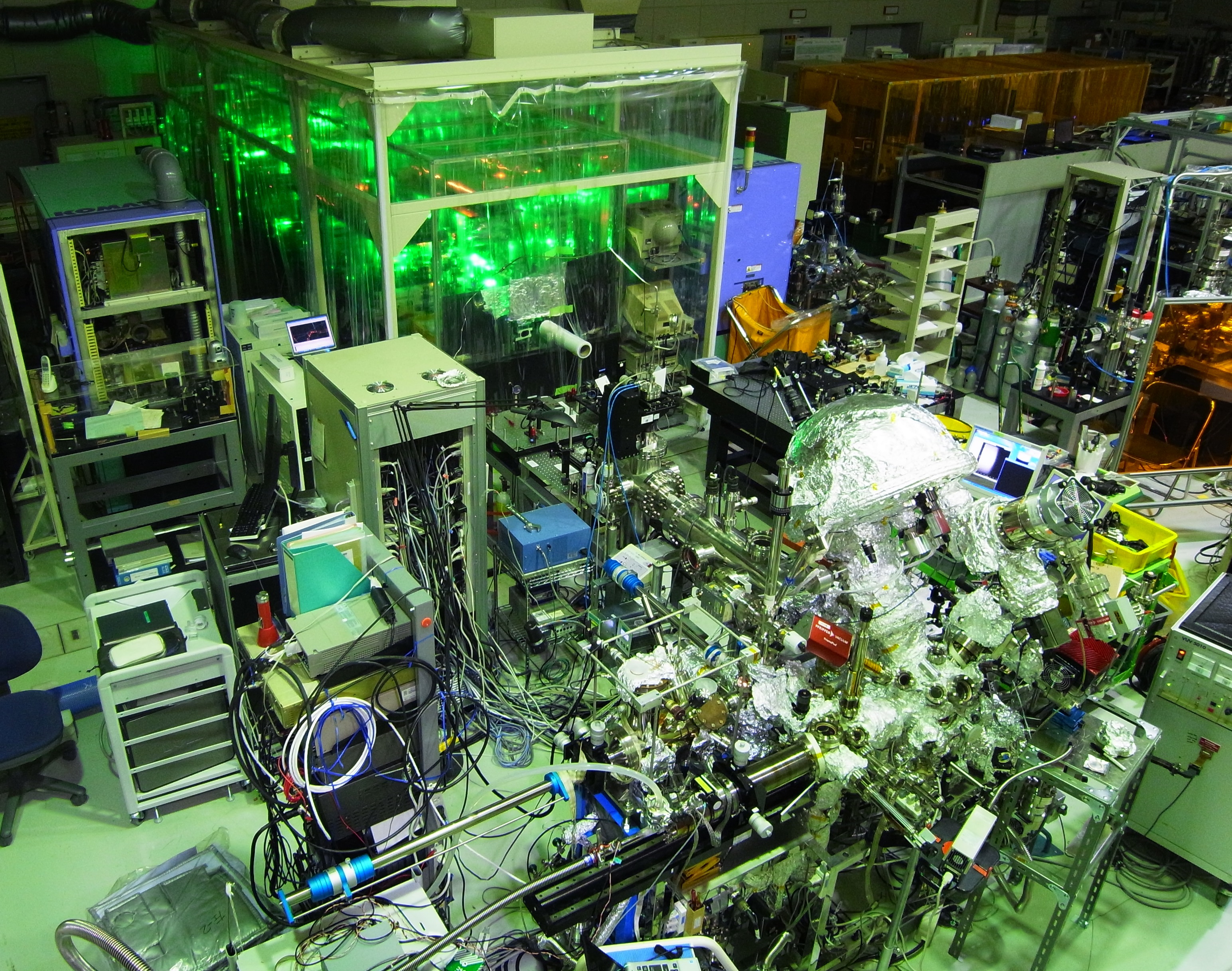 An extensive jumble of metal objects and cables. In the top of the image a cabinet glows green.