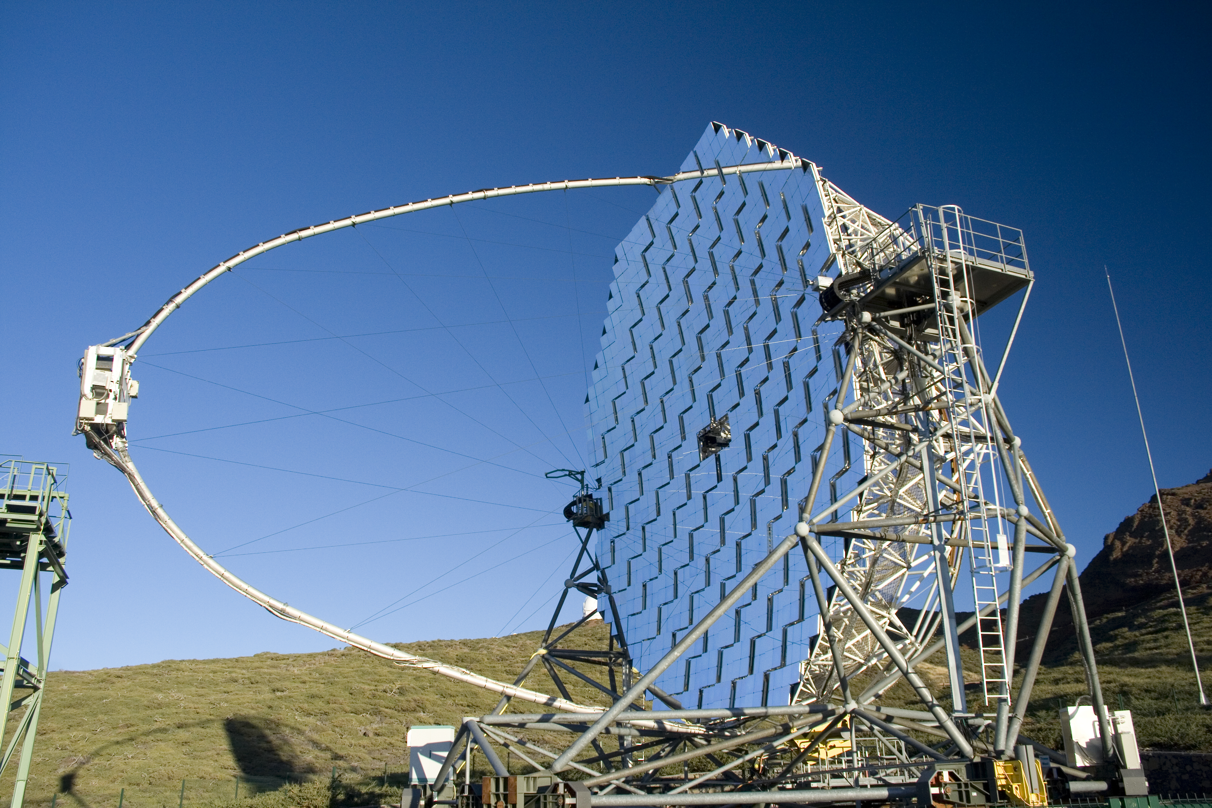 Blue sky with a large concaved mirror like structure in the middle distance