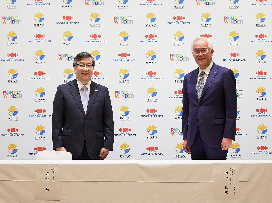 Two men standing in front of a backdrop of logos