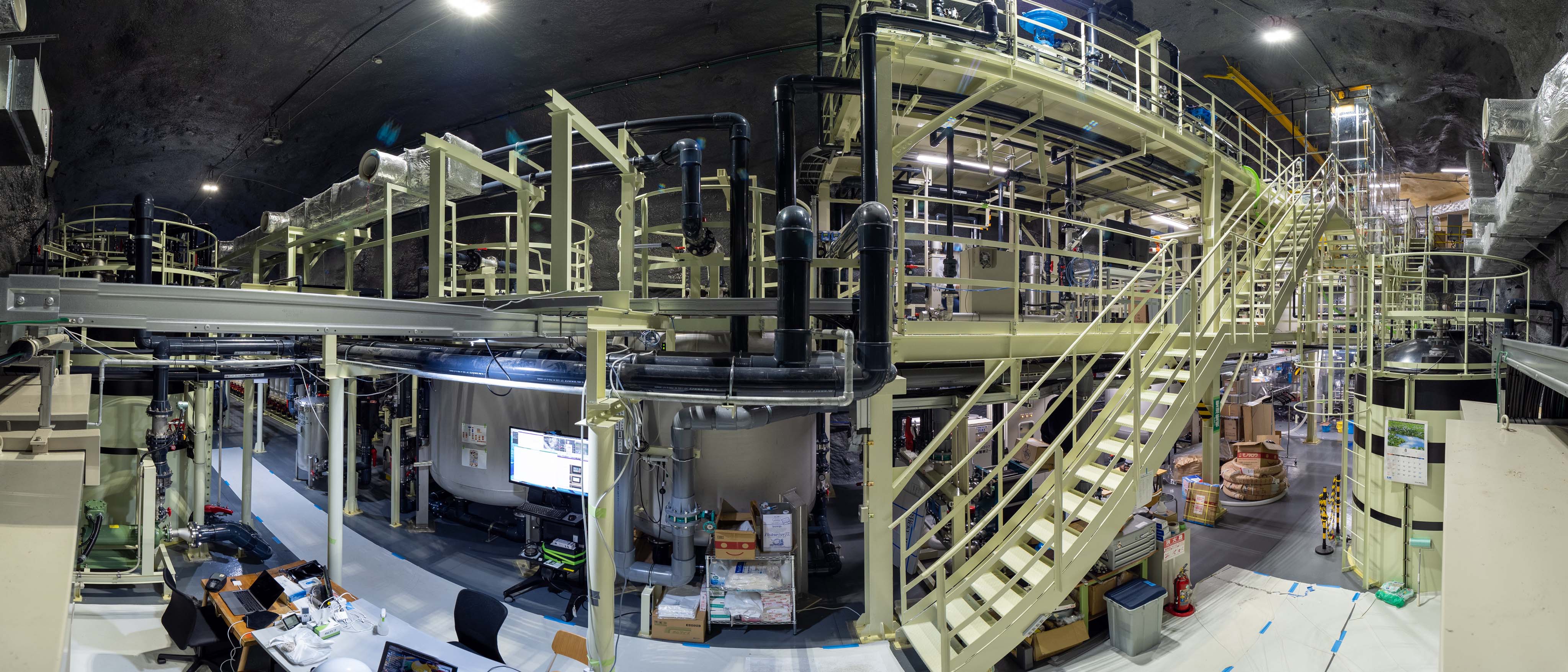 A large underground cavern housing pipes, staircases and various metal structures.