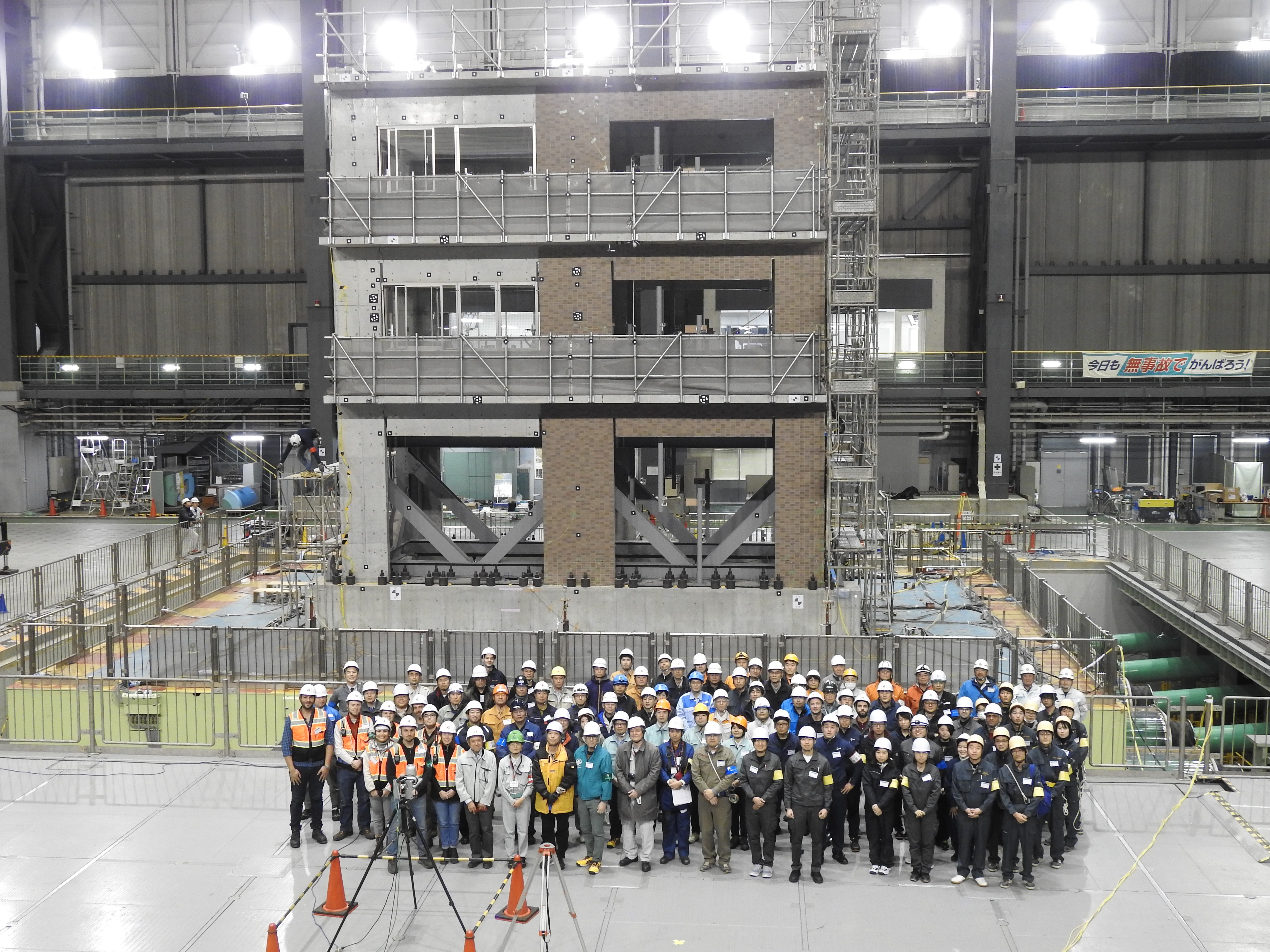 A crowd of people stand in front of a grey and brown concrete building