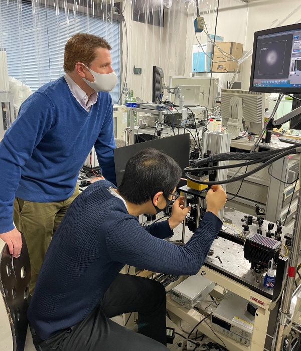 Two male researchers, one standing the other sitting, in a lab.