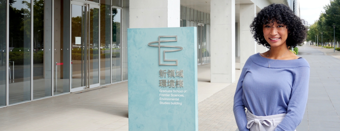 Student standing in front of the entrance to a research building