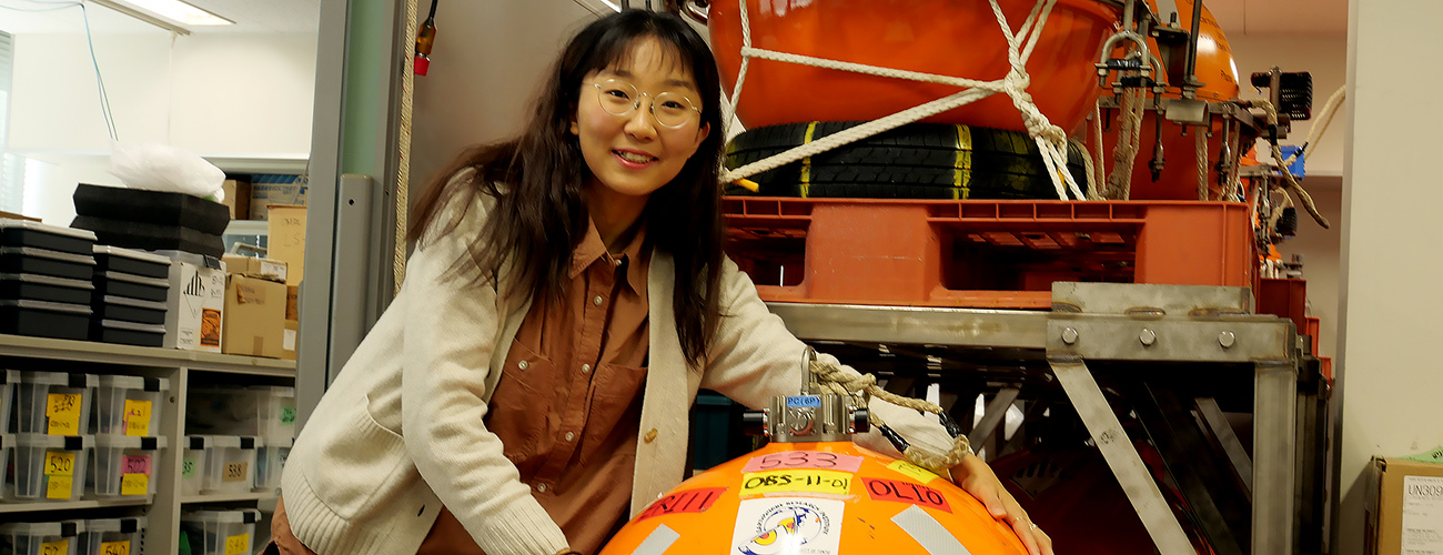 Student standing in front of a seismometer