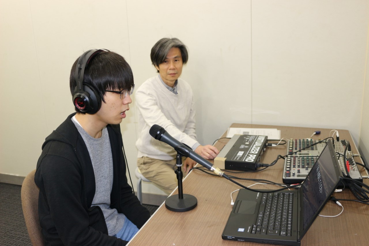 Professor Imamizu and a participant sitting at a desk and carrying out the experiment.