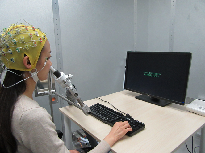 A participant at a computer, wearing an EEG cap while using the odor delivery device. 