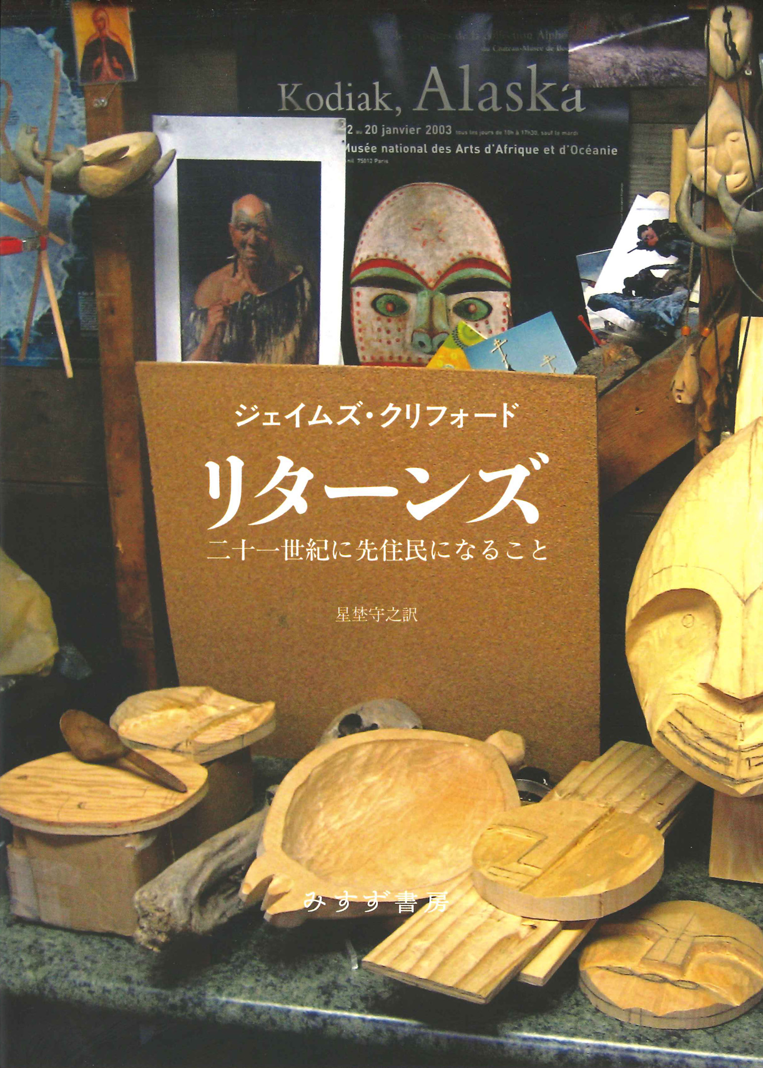 Several Indigenous masks made from wood on the table and several photos of Indigenous people and a poster of a mask on the wall 