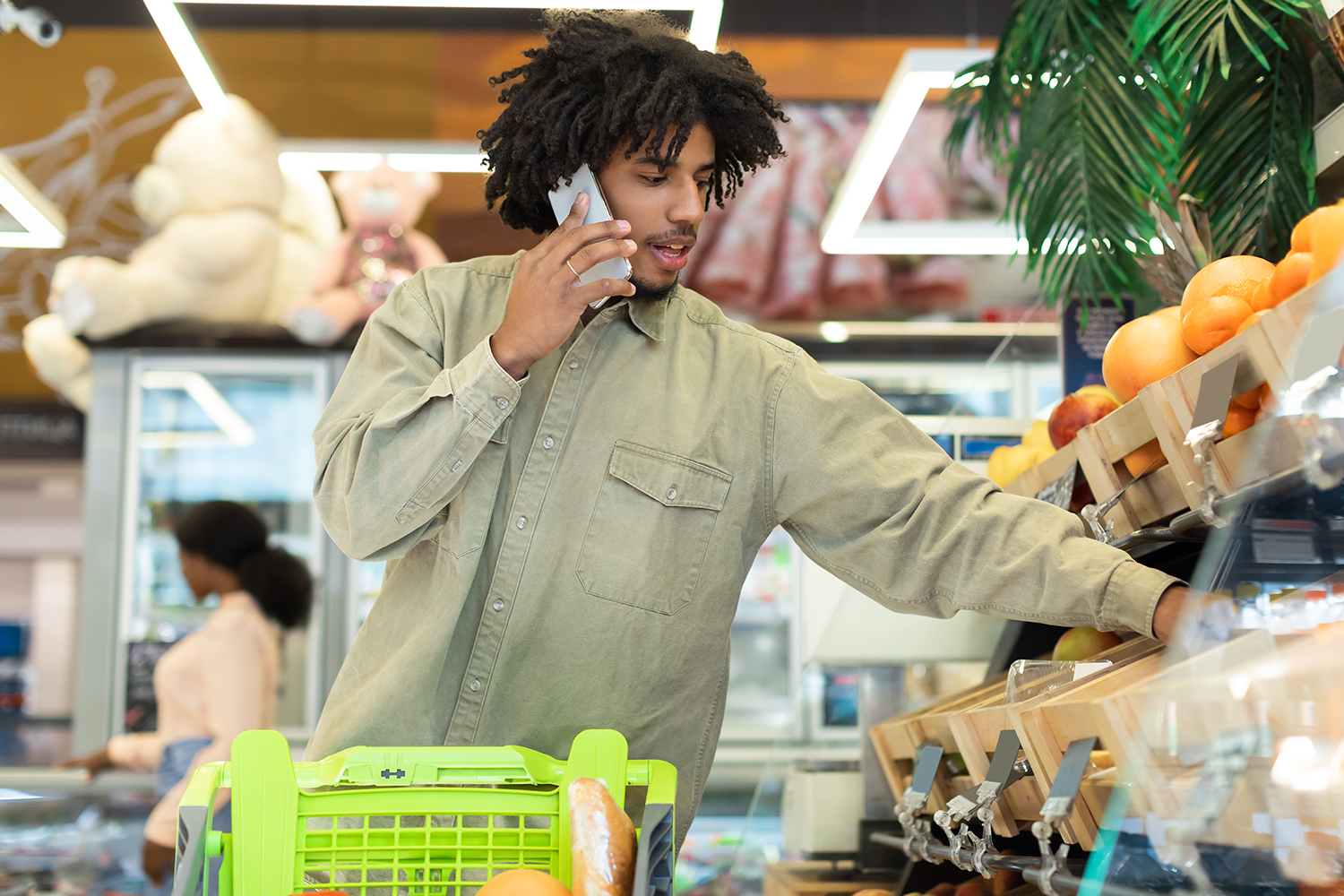 A man shopping for fruit in the supermarket while talking on the phone. 