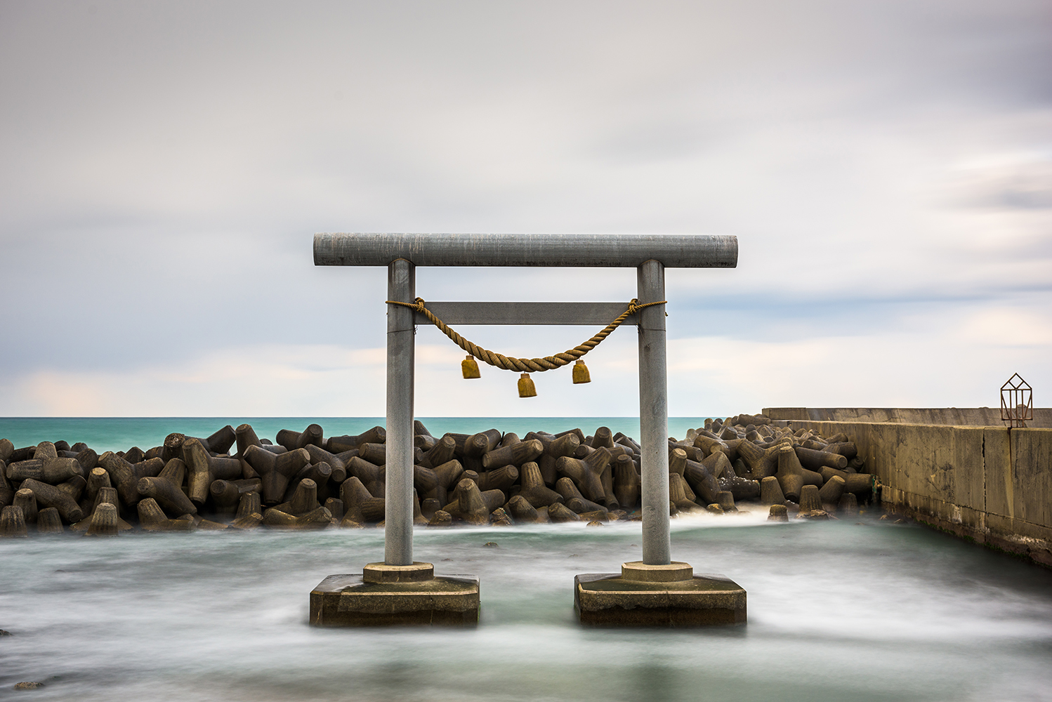 Grey, concrete Torii gate in the sea in Japan.