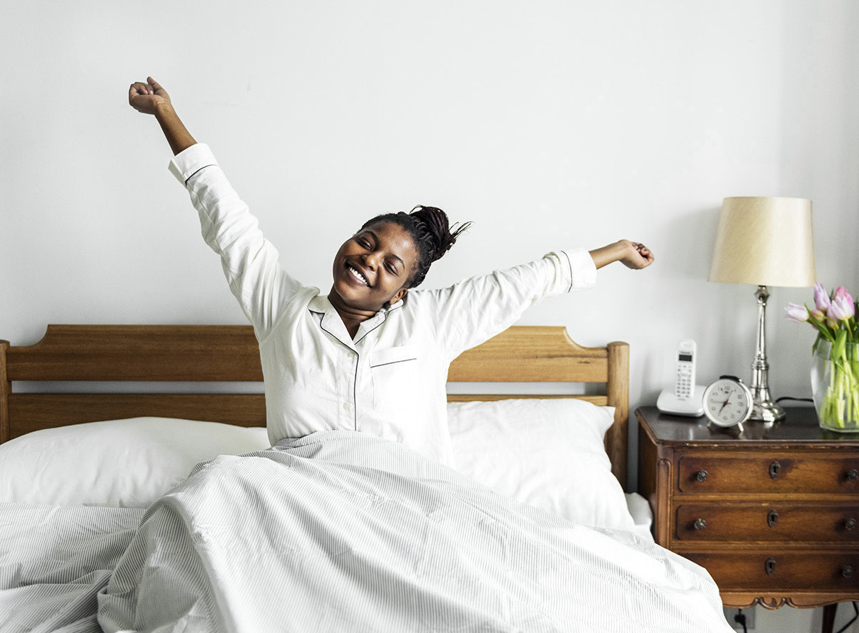Young woman stretching in bed looking happy and well rested.