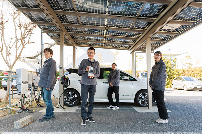 Photo of Yanekara staff posing in front of electric vehicle