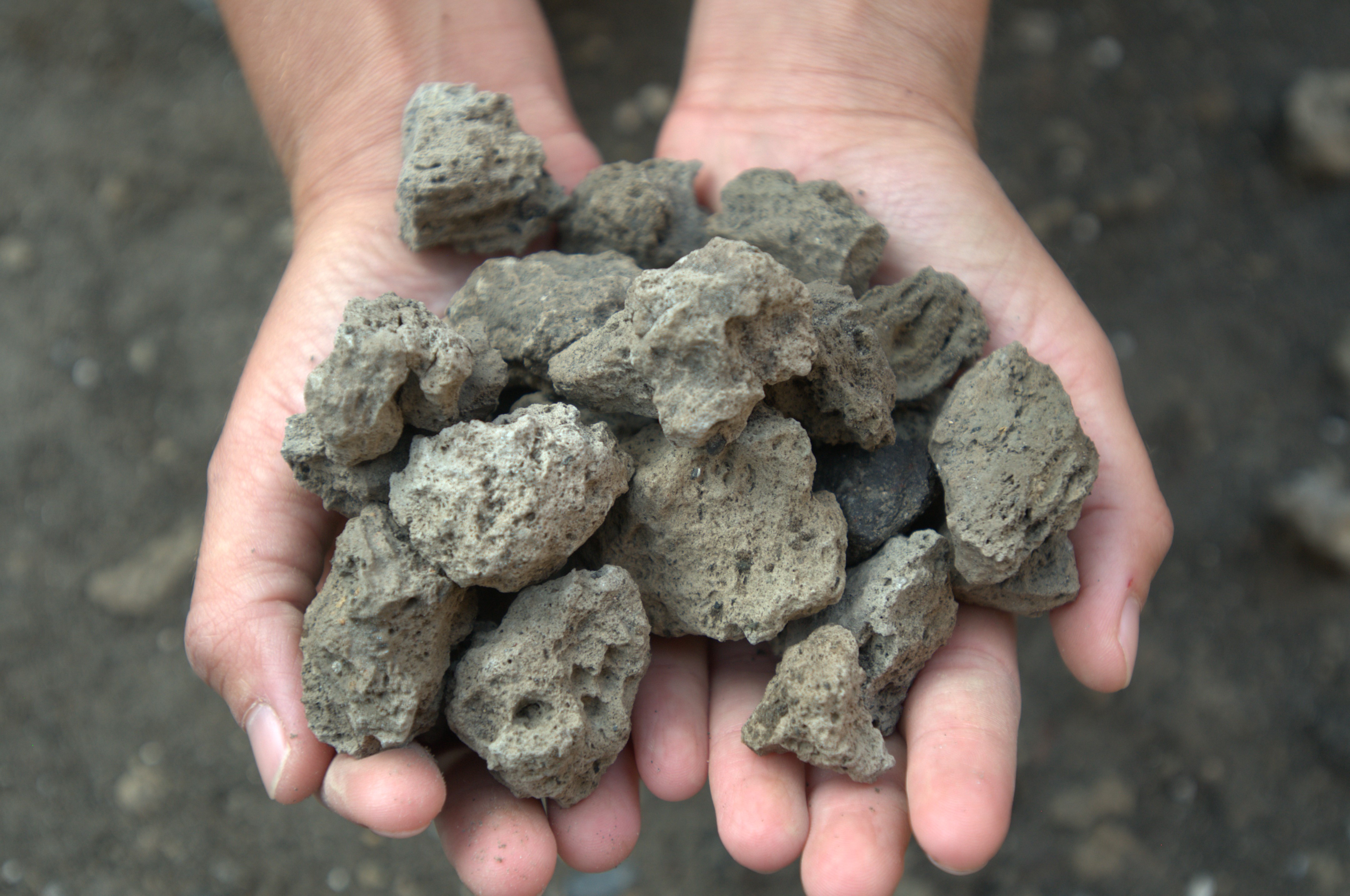 Two hands holding a pile of stones