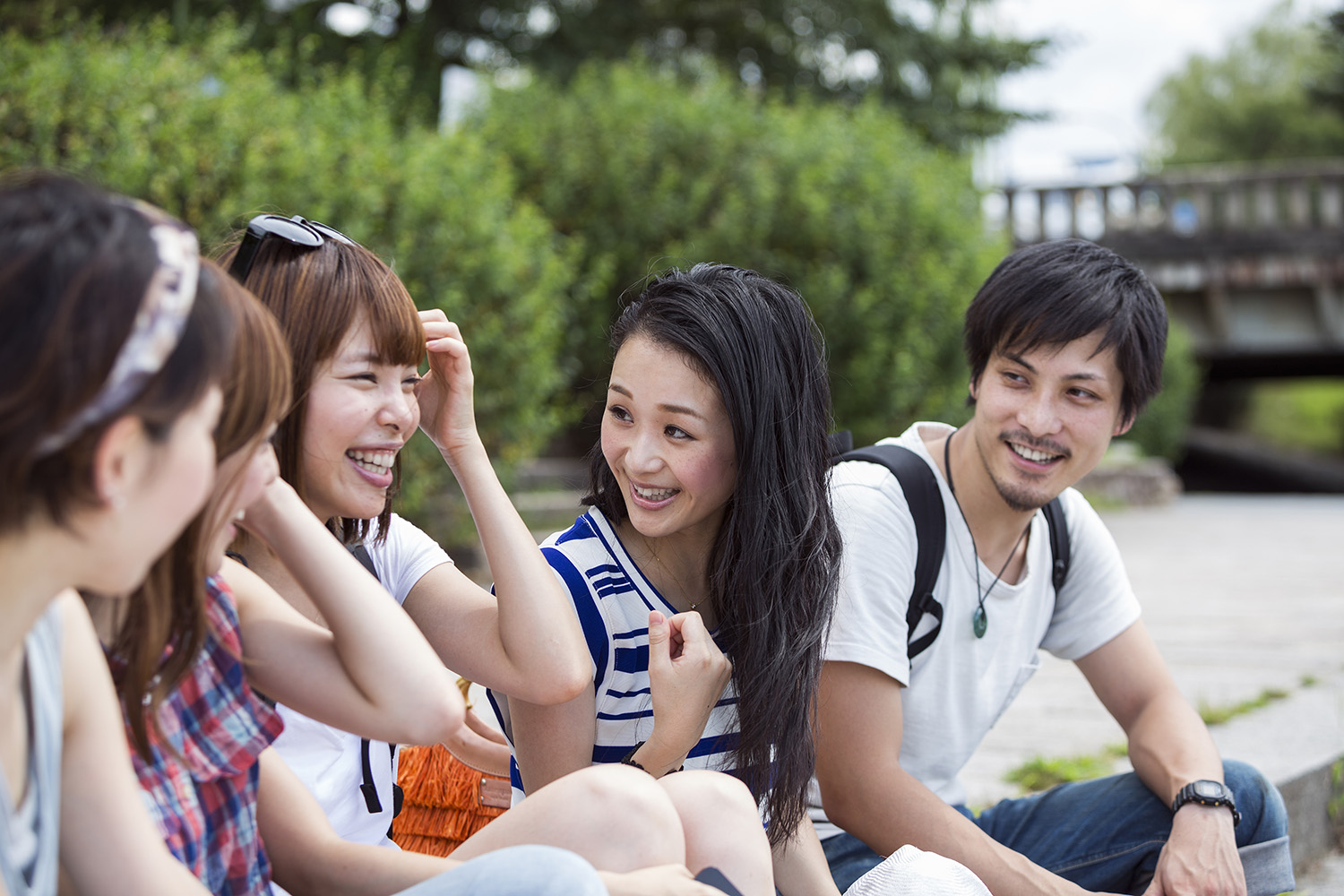 A group of Asian friends sitting outside and chatting happily.