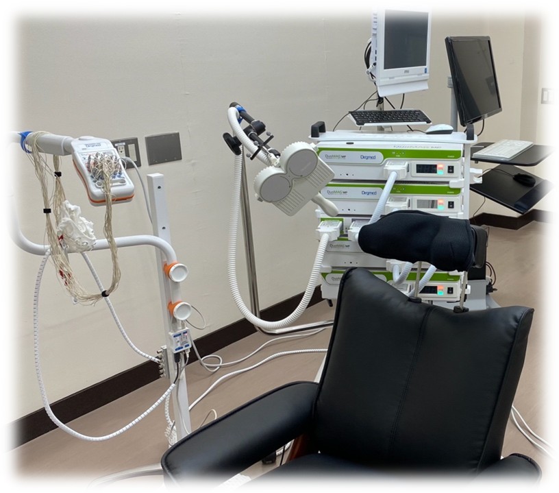 A dark chair in a grey room with white medical machines around it
