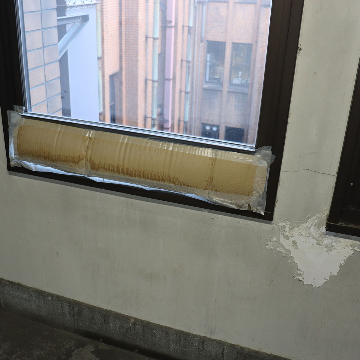 閉じなくなった廊下の窓を厚紙で補修