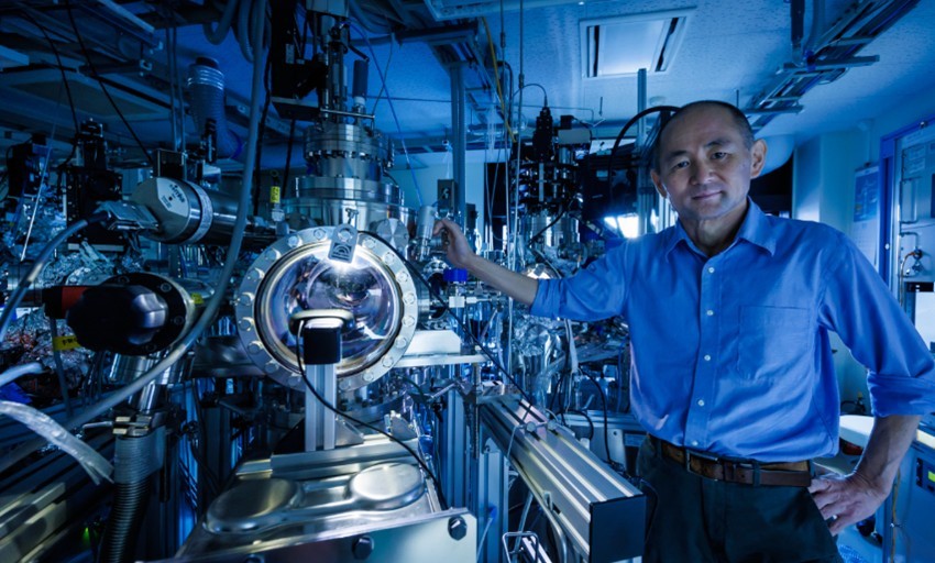 Photo of Professor Taro Hitosugi standing beside his team's autonomous experiment system.