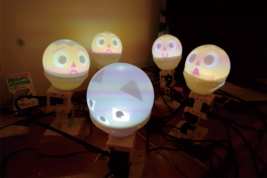 複数の丸いボールに様々な表情のイラストが投影されている