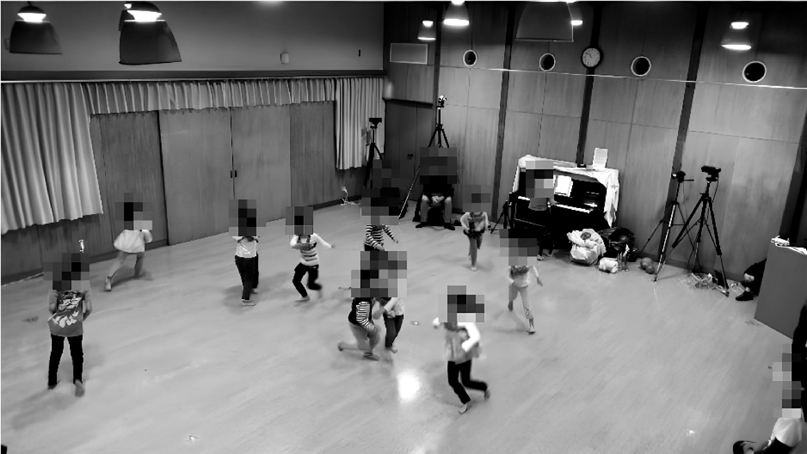 Black and white photograph of a school hall with children with blurred faces running.