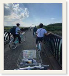 橋の上で自転車をこぐメンバー