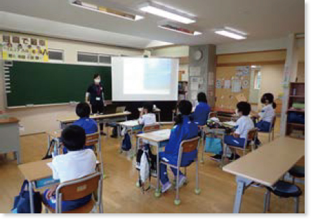 プロジェクター画面が映っている教室で授業をしている沿岸センターの職員と小学生