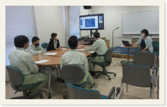 Zoomの画面が映っているモニターのある部屋で意見交換会に参加する教職員