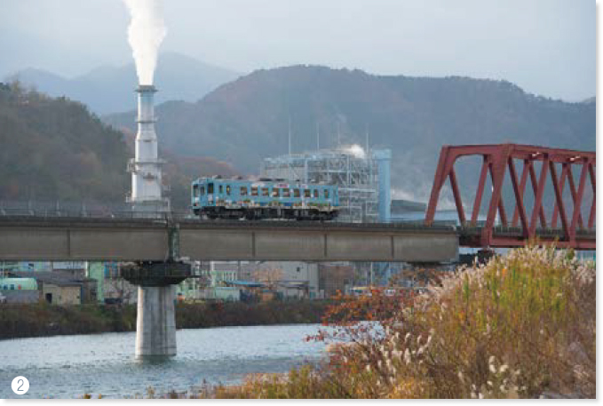 甲子川橋梁を渡る三陸鉄道の車両と製鉄会社の煙突