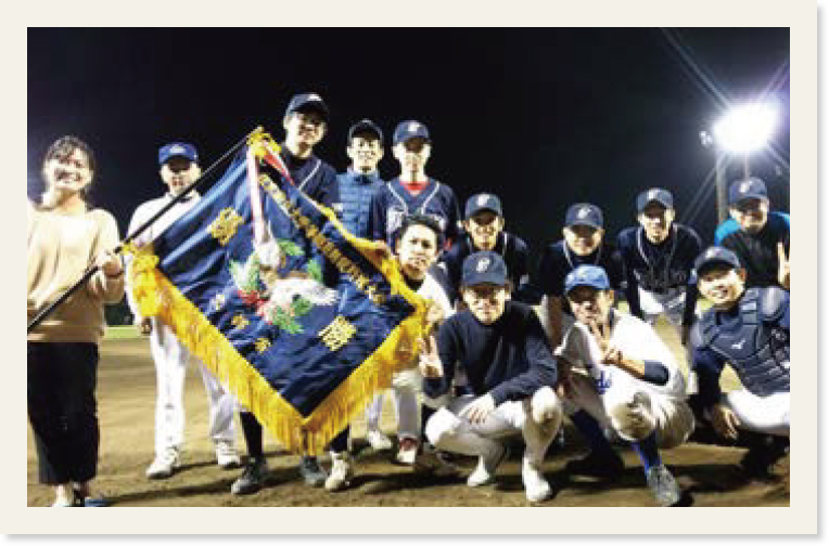 野球チームのメンバー12人と「在京国立大学等職員懇親野球大会」の優勝旗を持つ女性