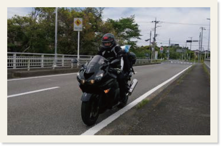 片側1斜線の道路でカワサキ製のバイクに乗る西村氏