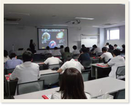 超新星爆発のプロジェクター映像の横で説明する川越氏とそれを聴く高校生