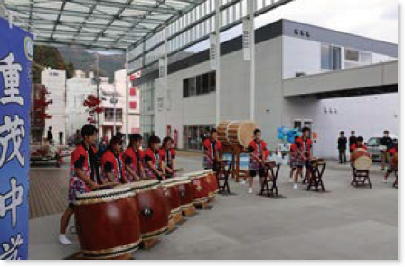 赤い法被を着てハの字に並んで太鼓の演奏をする中学生
