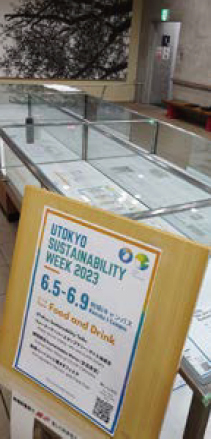 「UTOKYO SUSTAINABILITY WEEK 2023」と書かれた立て看板とガラスケース内に展示されている書類