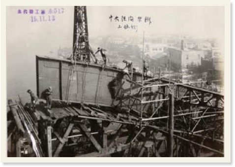 「永代橋工事」の印が押されている写真。橋のアーチ部分を建設している人々が映っている