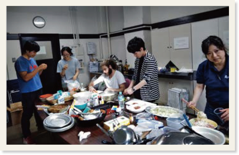 長机の上で学生と共に料理を作っている様子